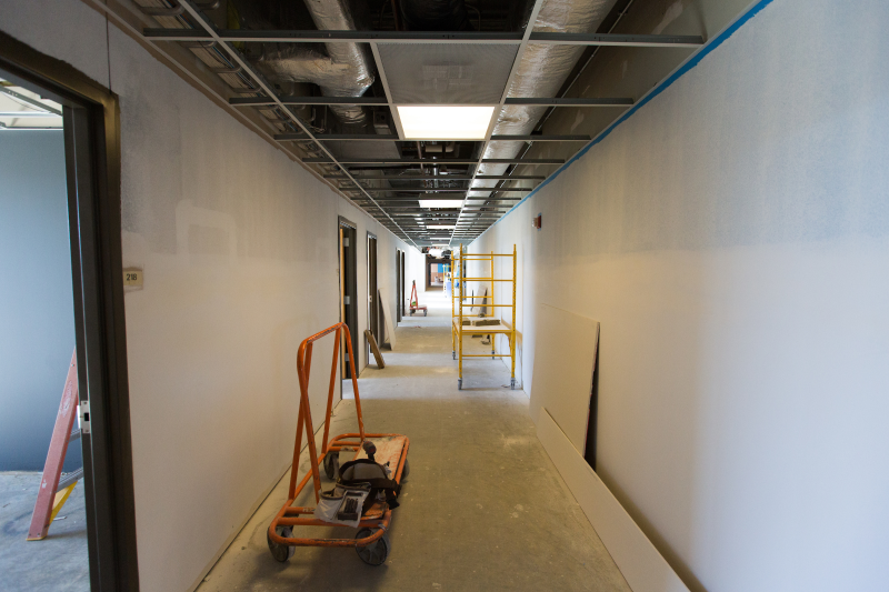 Hallway under construction with drywall and vents visible